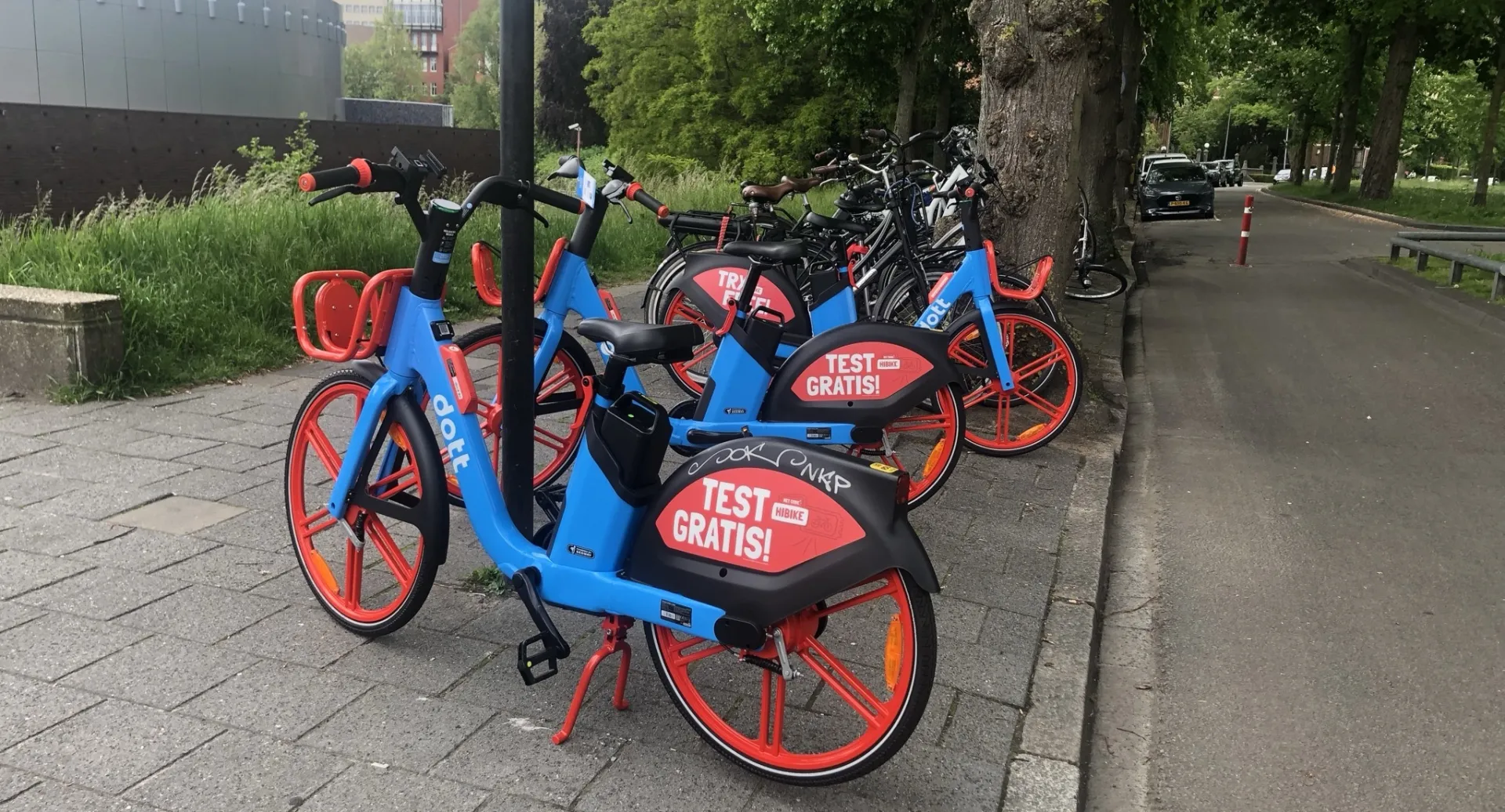 Blauwe en rode deelfietsen geparkeerd langs een straat
